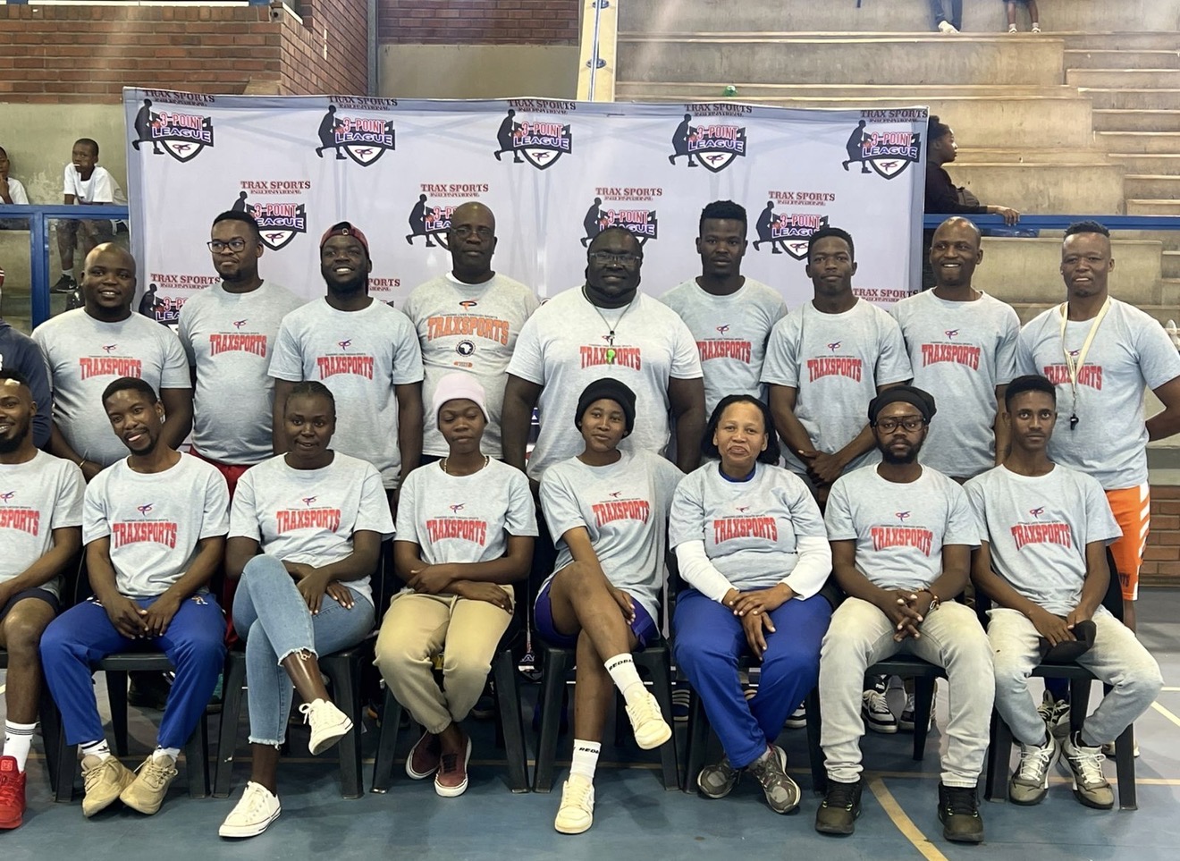 Trax Sports coaching staff gathered on a basketball court with a 3-Point League backdrop